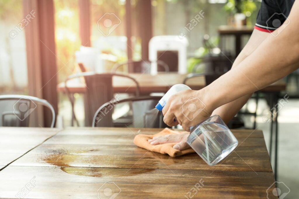 94528490 waiter cleaning the table with disinfectant spray in a restaurant